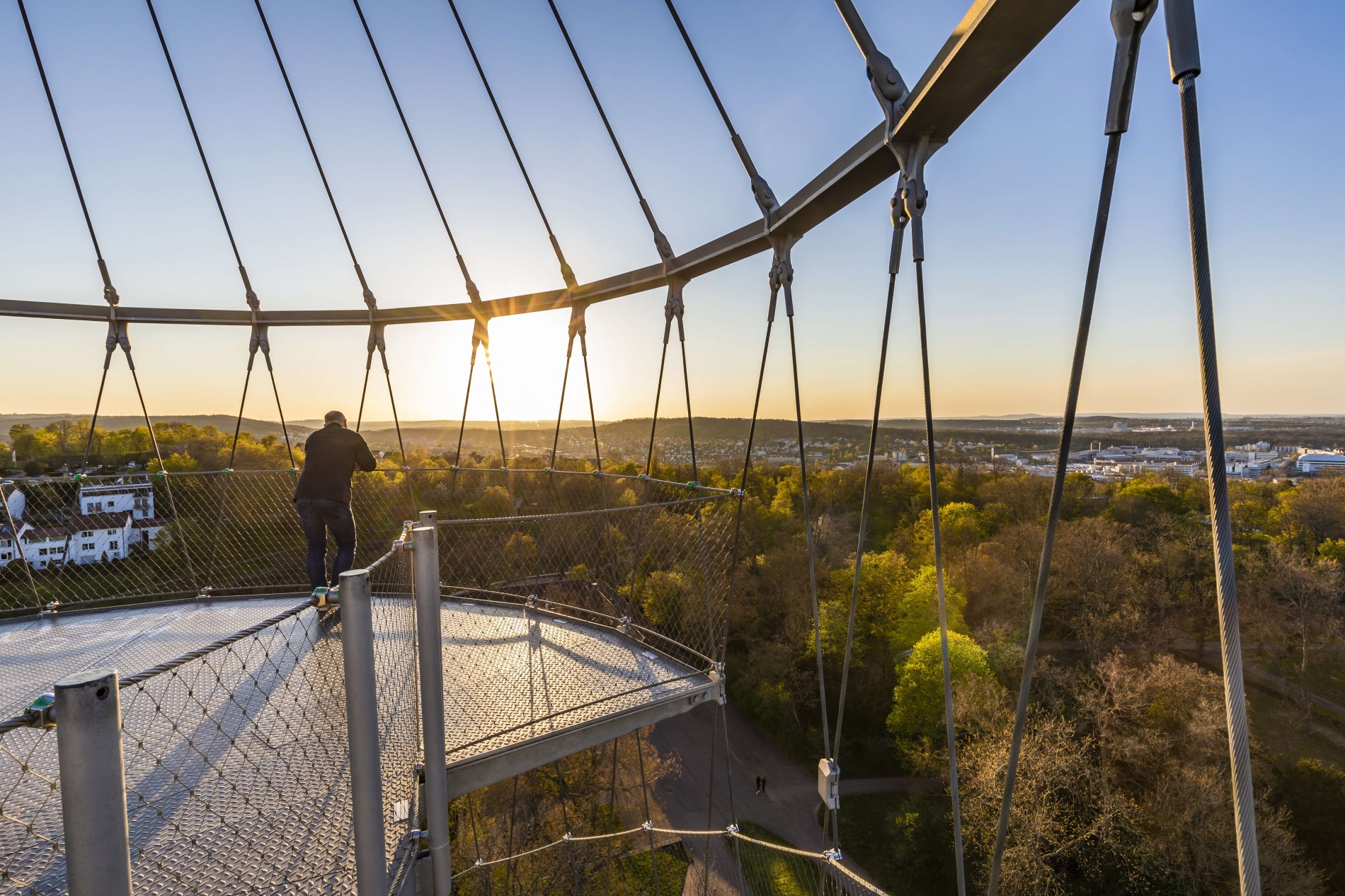Ein Mann steht auf der Aussichtsplattform des Killesbergturms. Er beobachtet den Sonnenuntergang.