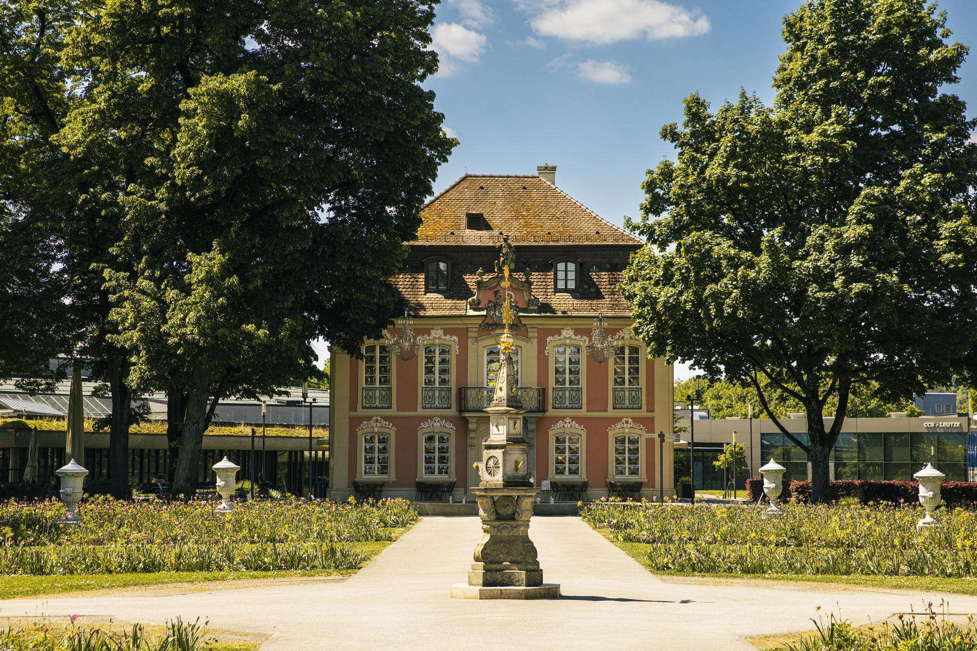 Rokokoschlösschen in Schwäbisch Gmünd umrahmt von zwei grünen Bäumen.